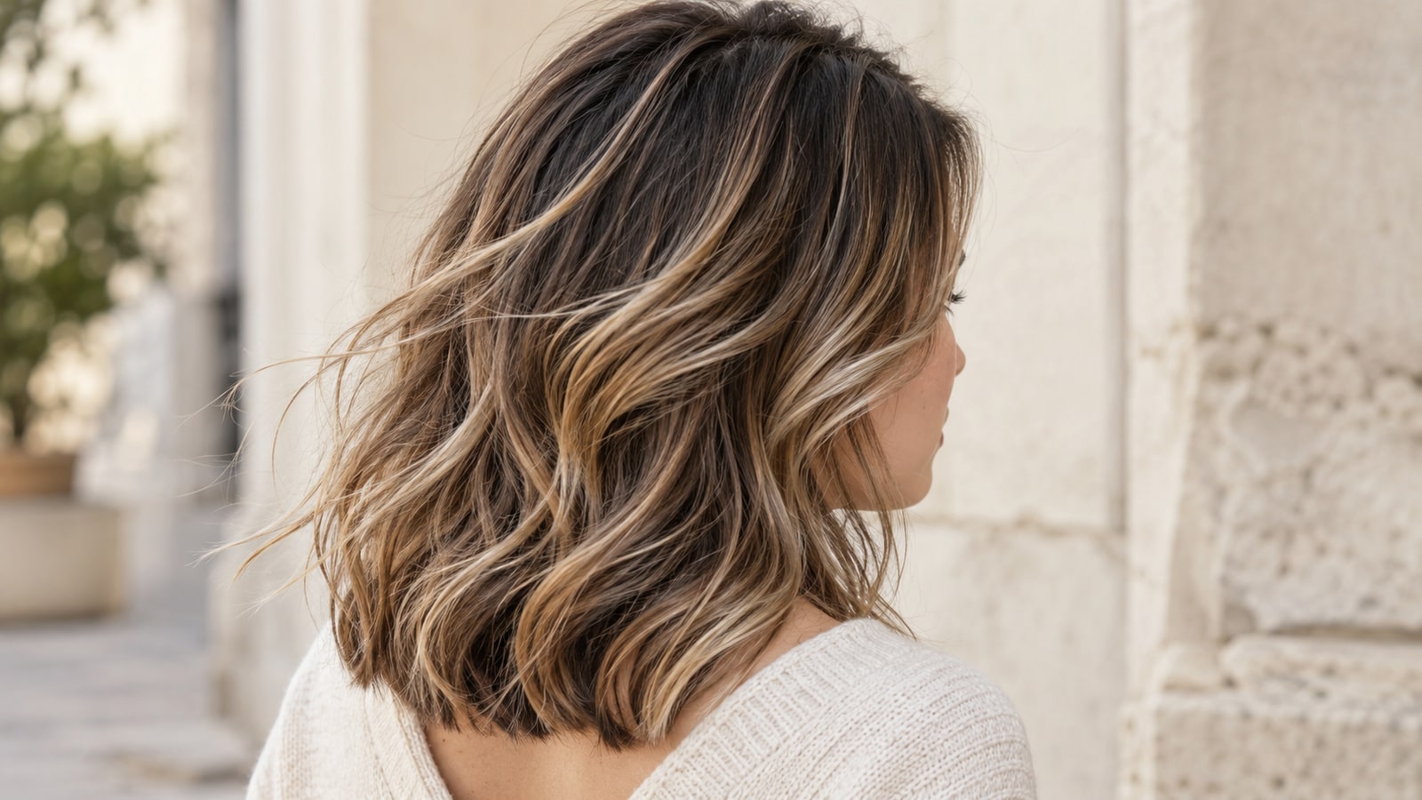 Rear three-quarter view of a textured shoulder-length lob with beige and caramel balayage ribbons moving in natural light